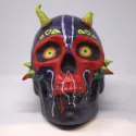 Black, red, and purple painted skull with neon details, spikes near the cheeks and horns.