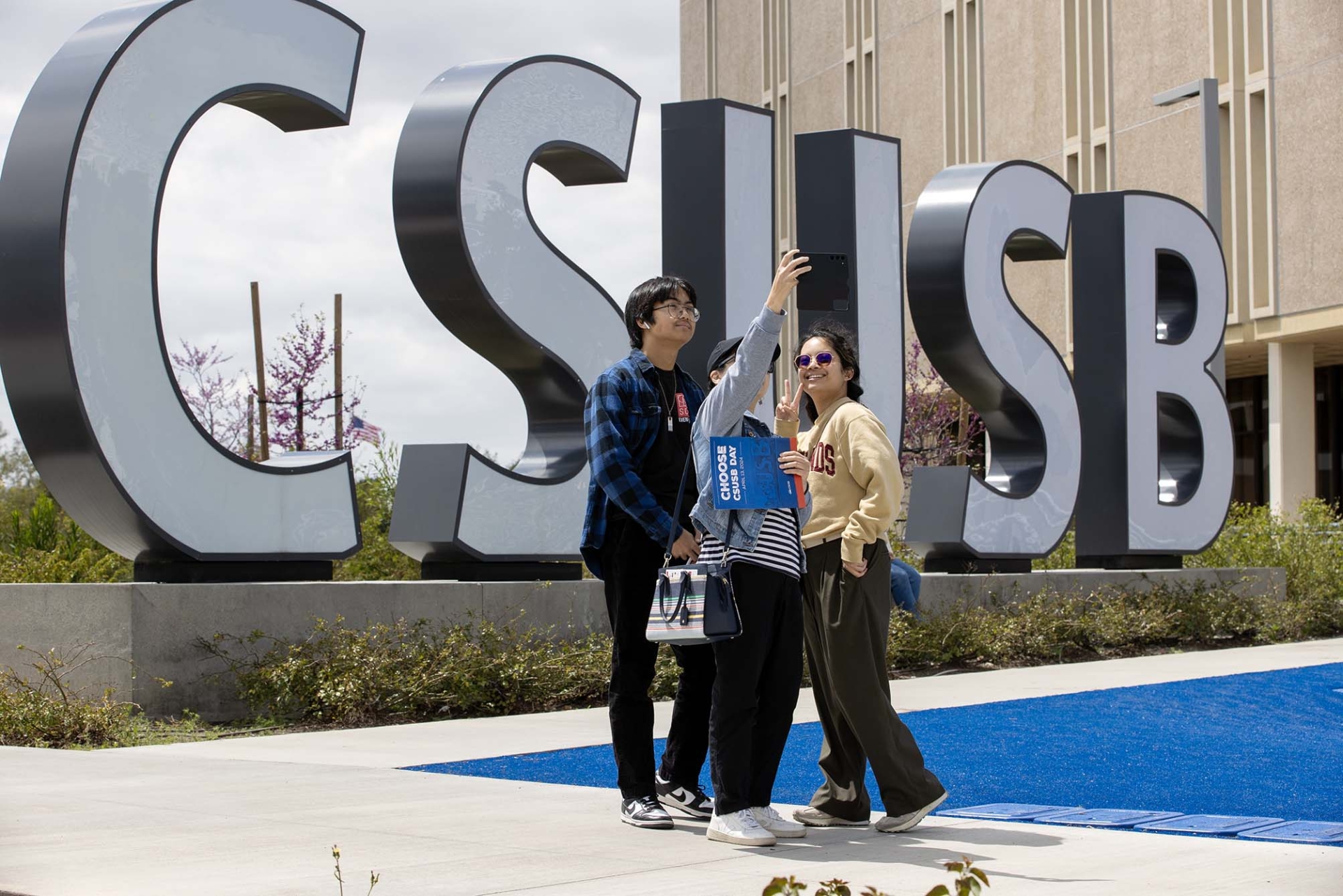 A group takes a selfie at the sprit letters during Choose CSUSB Day.