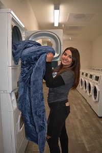 student at laundry mat taking blanket out of dryer