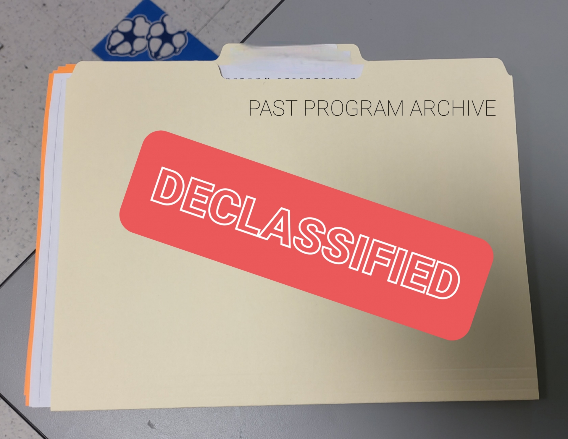 A photo of a manilla folder with the words "Past programs archive" and "Declassified" on it
