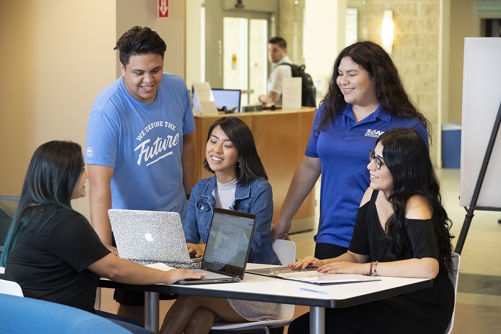 5 people sitting around a table working in a group