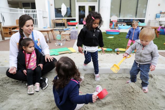 ITLS children and teacher playing in sand box