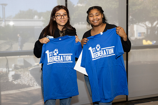 Two attendees hold up first-generation T-shirts