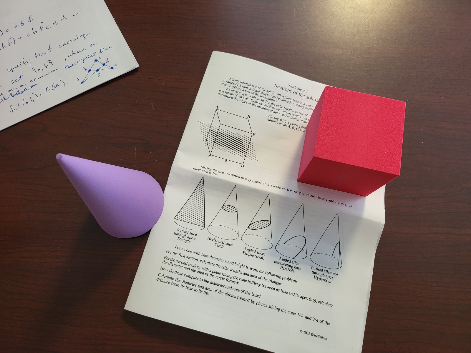 Geometry figures paired with paper containing volumetric formulae