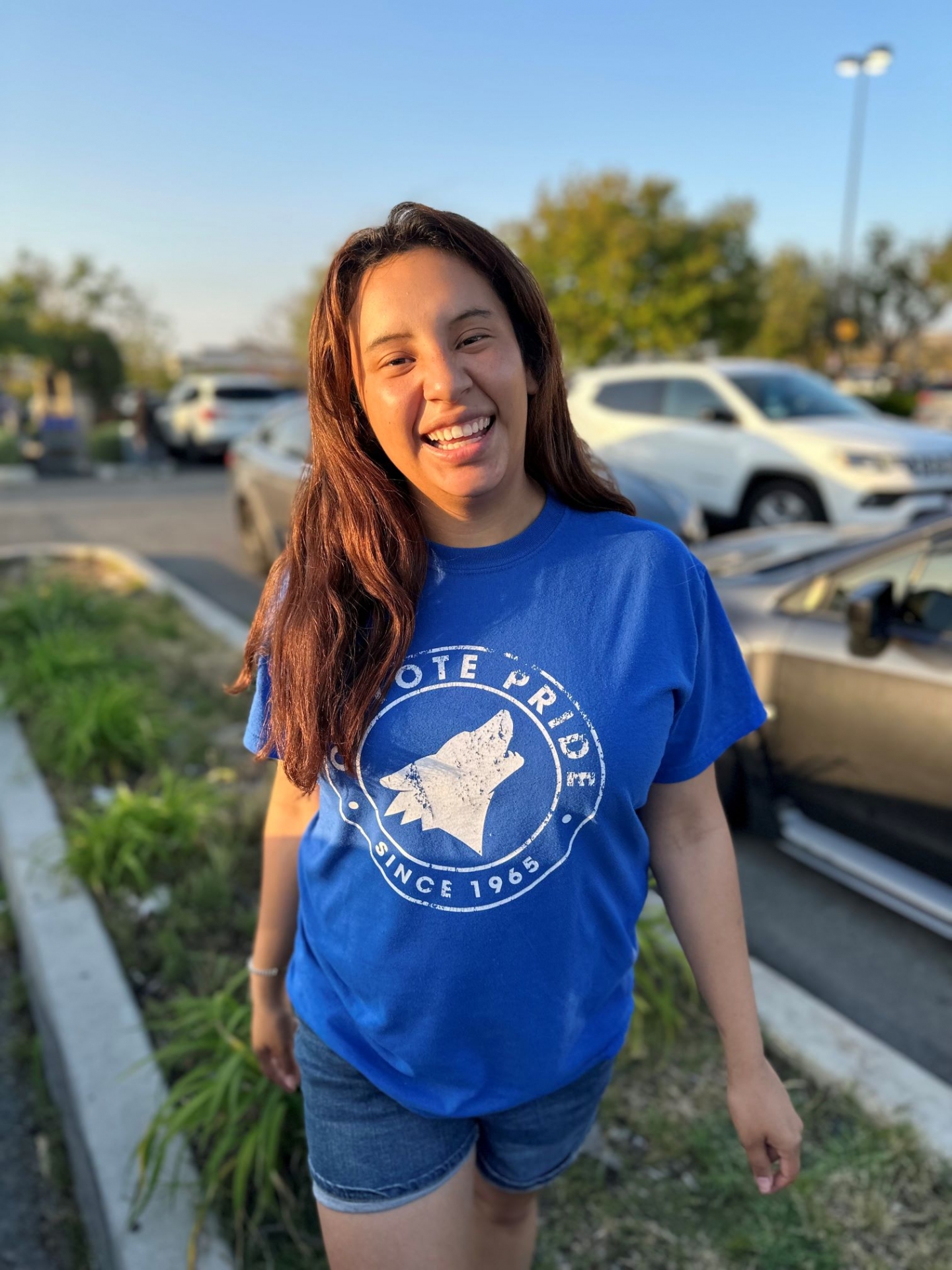 Young woman smiling outside wearing a blue CSUSB shirt