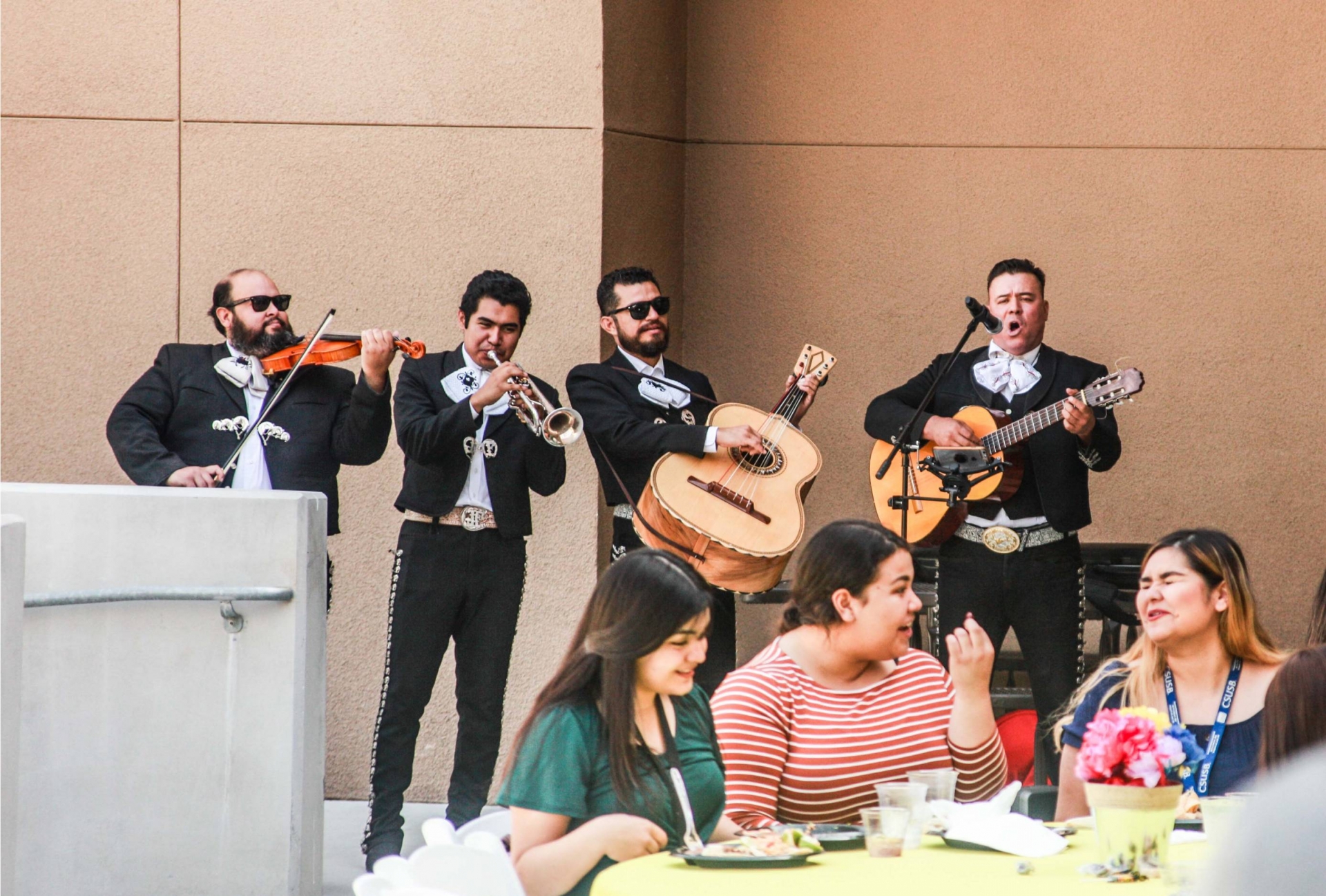 Mariachi playing behind tables of people eating