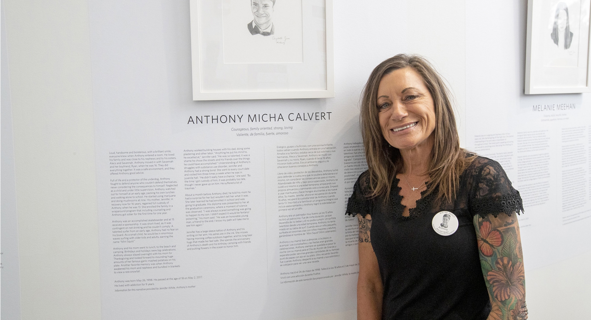 ​  Jennifer White, Anthony Calvert's mother, next to her son’s portrait at the INTO LIGHT exhibit at the CSUSB Anthropology Museum.  ​