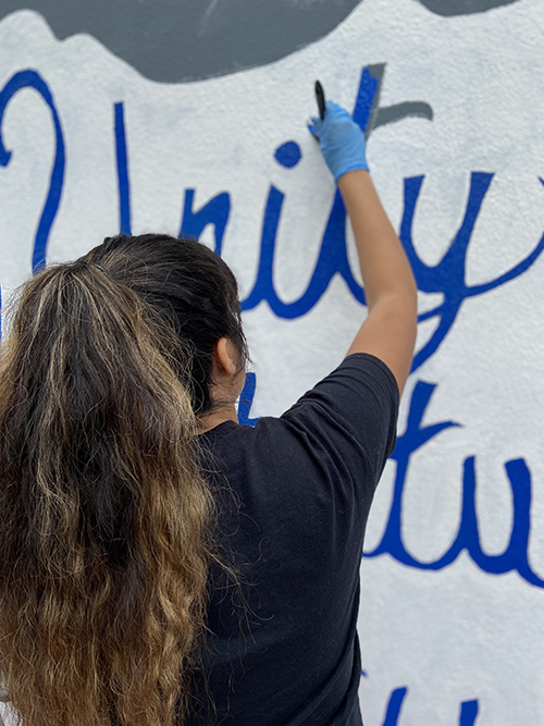 CSUSB student helping paint a mural at Orville Wright Middle School.