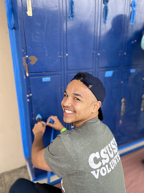 CSUSB student smiling for the picture as he put painter's tape around the school locker.