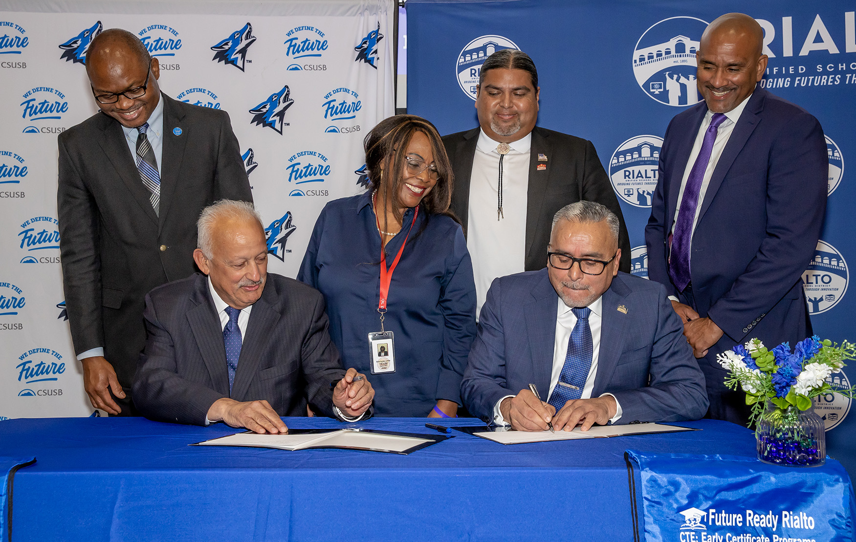Tomás D. Morales, (left) president of CSUSB, and Cuauhtémoc Avila, superintendent Rialto Unified School District, sign the memorandum of understanding formally launching the Teach Rialto initiative. Looking on from the back row, from left, Chinaka S. DomNwachukwu, dean of the James R. Watson & Judy Rodriguez Watson College of Education, CSUSB; Stephanie E. Lewis, Rialto Unified School District board member; Edgar Montes, Rialto Unified School District board member; and Rafik Mohamed, provost and vice president of Academic Affairs, CSUSB.