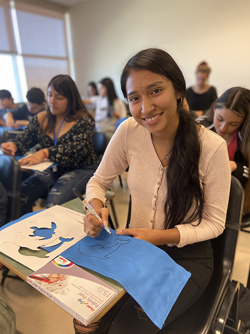 CSUSB PDC student decorating the duffel bag for Make A Difference Day.