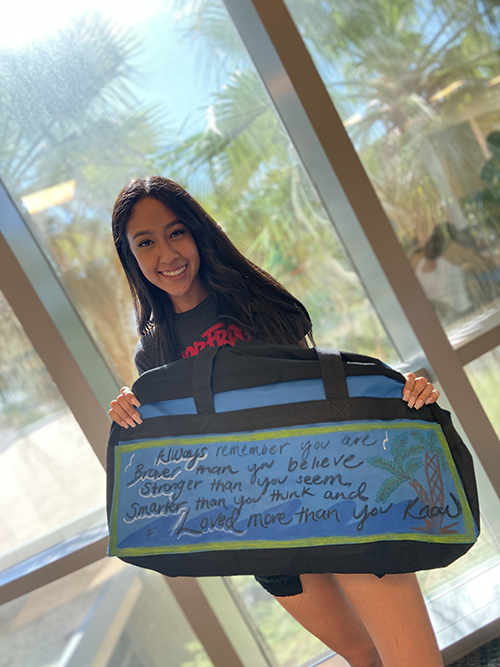 CSUSB PDC student showing off her decorated duffel bags.