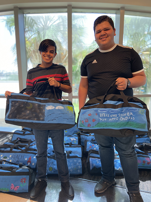 CSUSB PDC students showing off their decorated duffel bags.