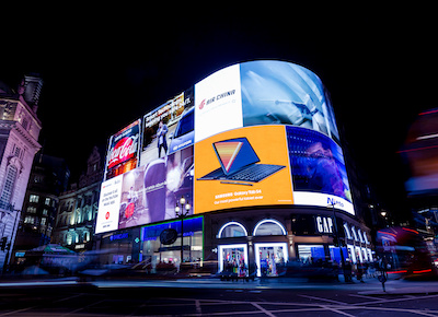 Street corner with multiple screens showing advertisements