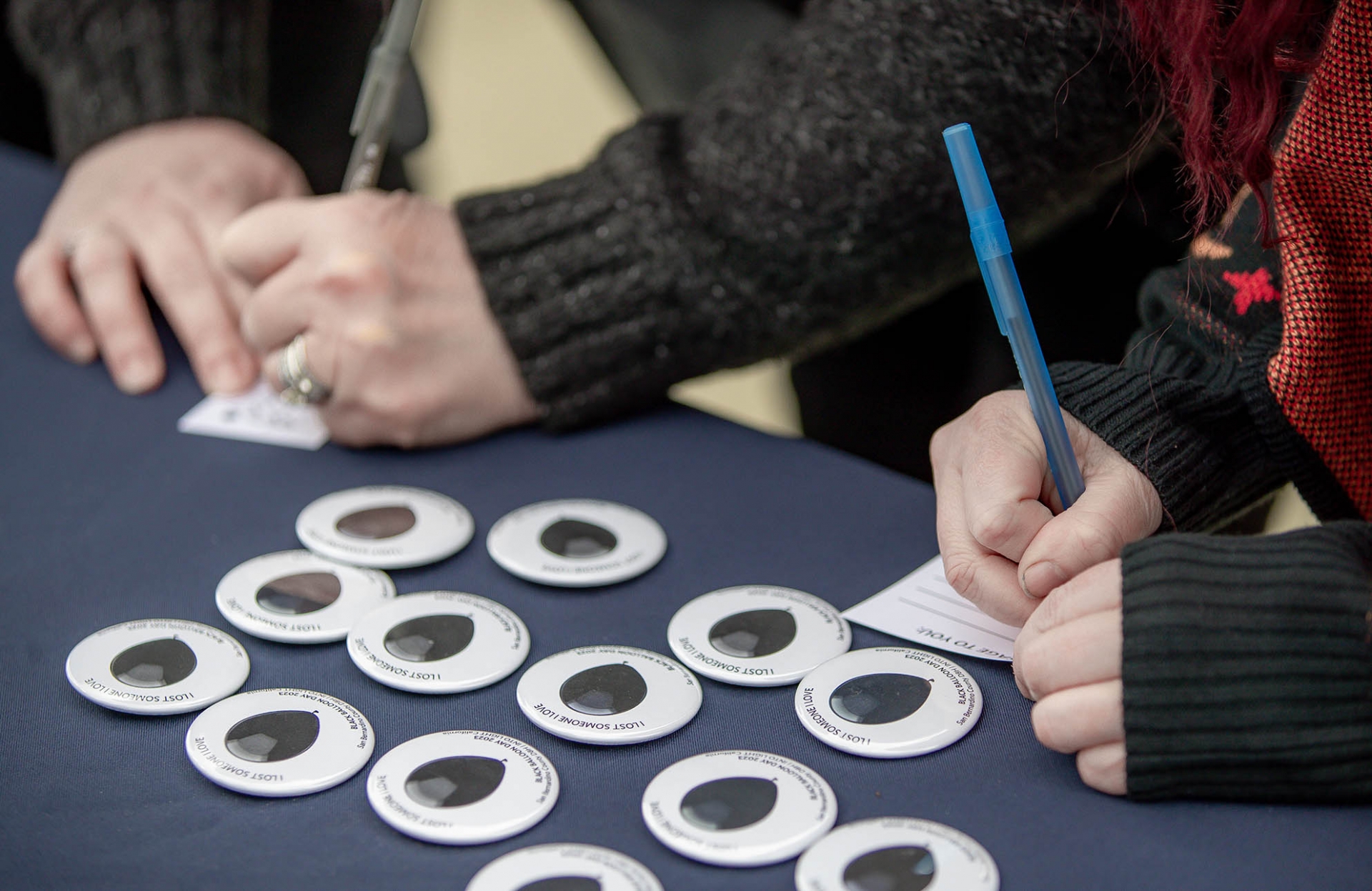 Visitors to a Black Balloon Day information table on Coyote Walk write messages to loved ones lost to drug overdoses. The event on March 6 raised awareness of the dangers of drug overdoses and substance use disorder.