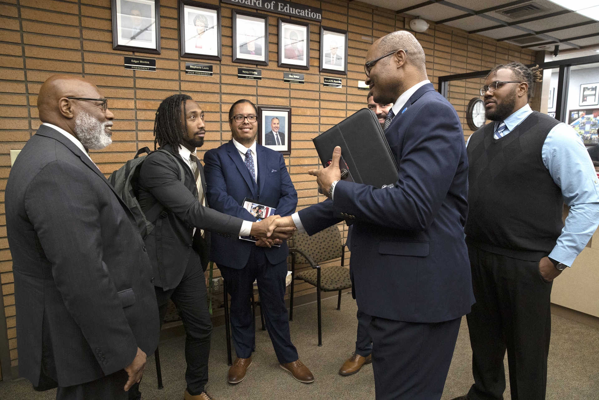 Chinaka DomNwachukwu, second from right, dean of the Watson College of Education, shakes hands with a participant of Project Impact at a Rialto Unified School District board meeting in August 2022