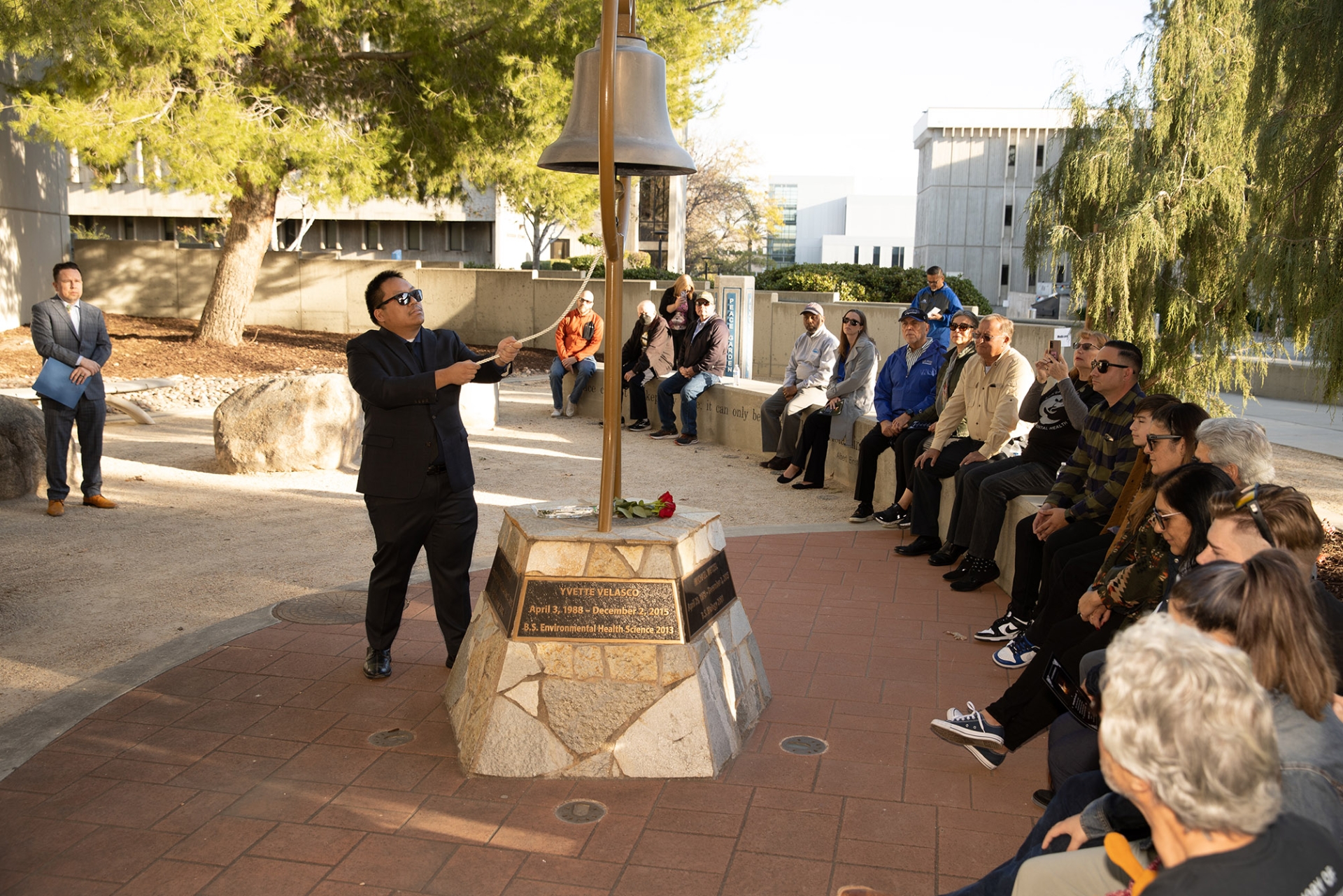 Michael Nguyen, a former faculty member in the Department of Health Science and Human Ecology, rings the bell at the Peace Garden on the Day of Remembrance, Dec. 2.