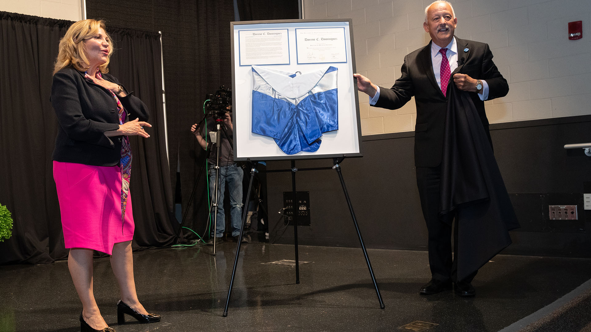 Dorene C. Dominguez (left) reacts as CSUSB President Tomás D. Morales presents her with a framed copy of her honorary doctorate certificate. Dominguez was awarded an Honorary Doctor of Humane Letters by CSUSB at the May 2023 Commencement.