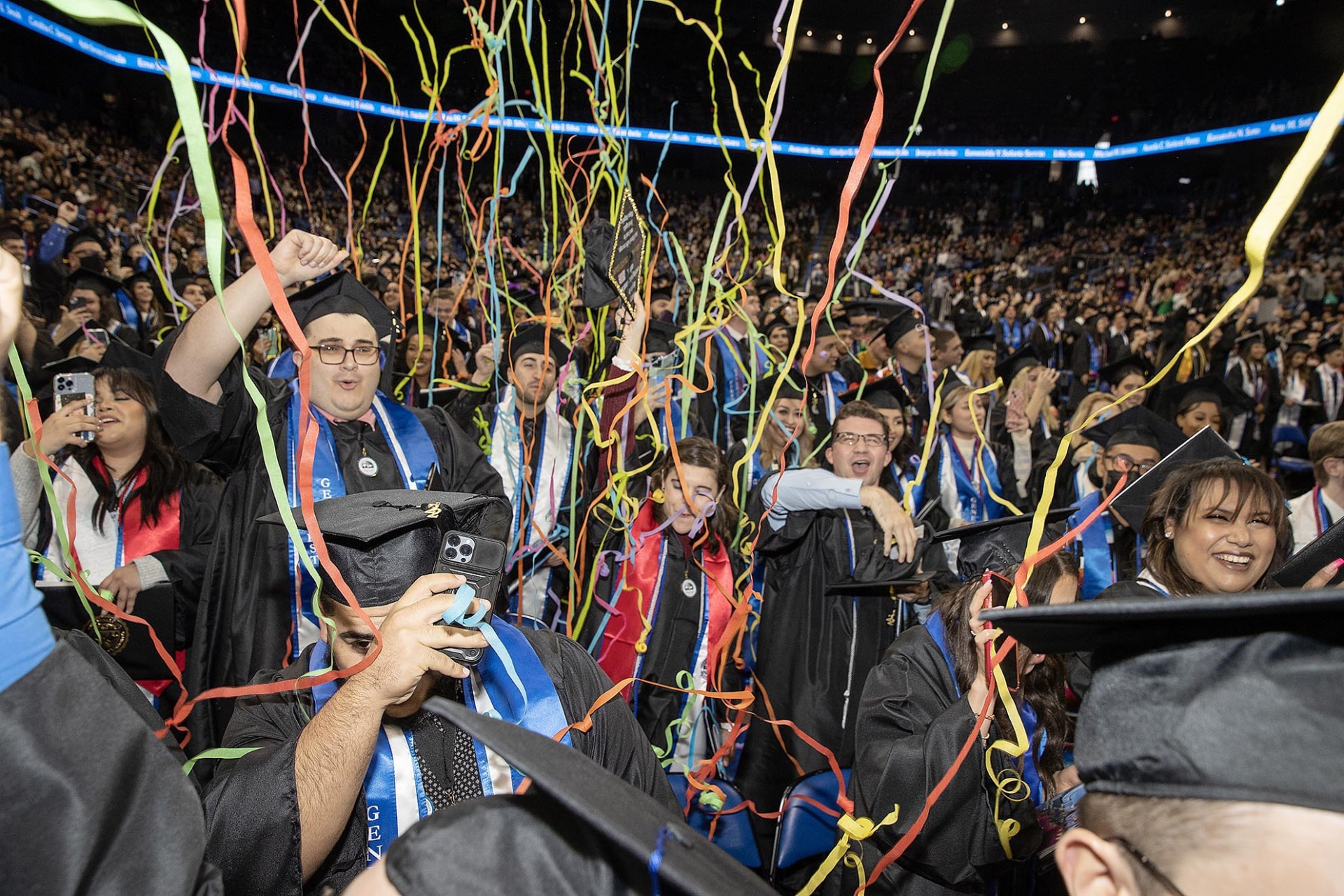 Celebrating at the end of the commencement ceremony as streamers drift down.