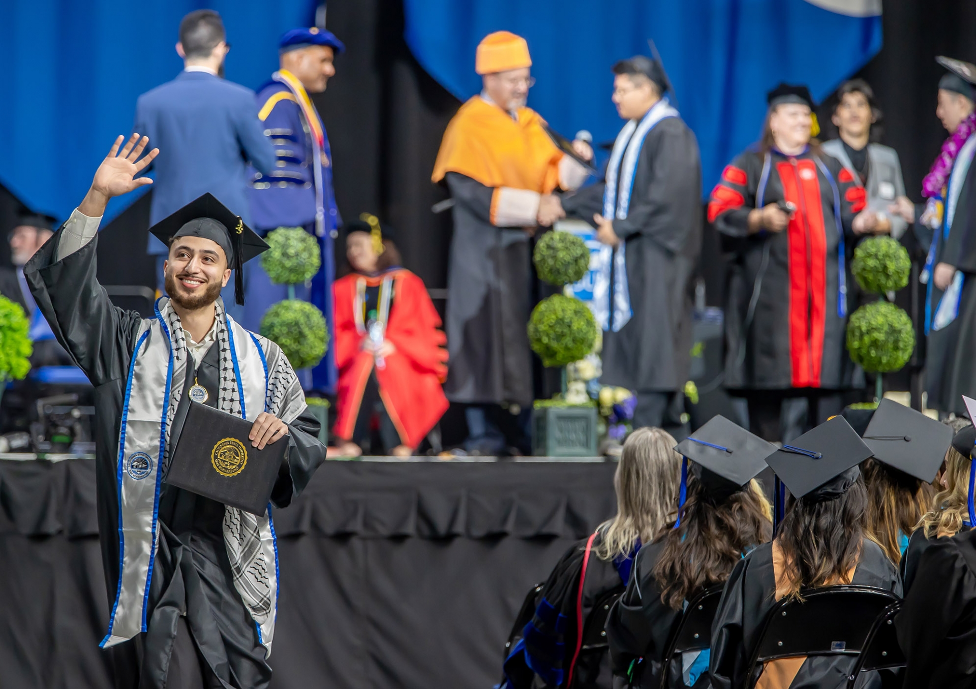 A graduate waves to the crowd during the Jack H. Browd College of Business and Public Administration’s ceremony on May 20.