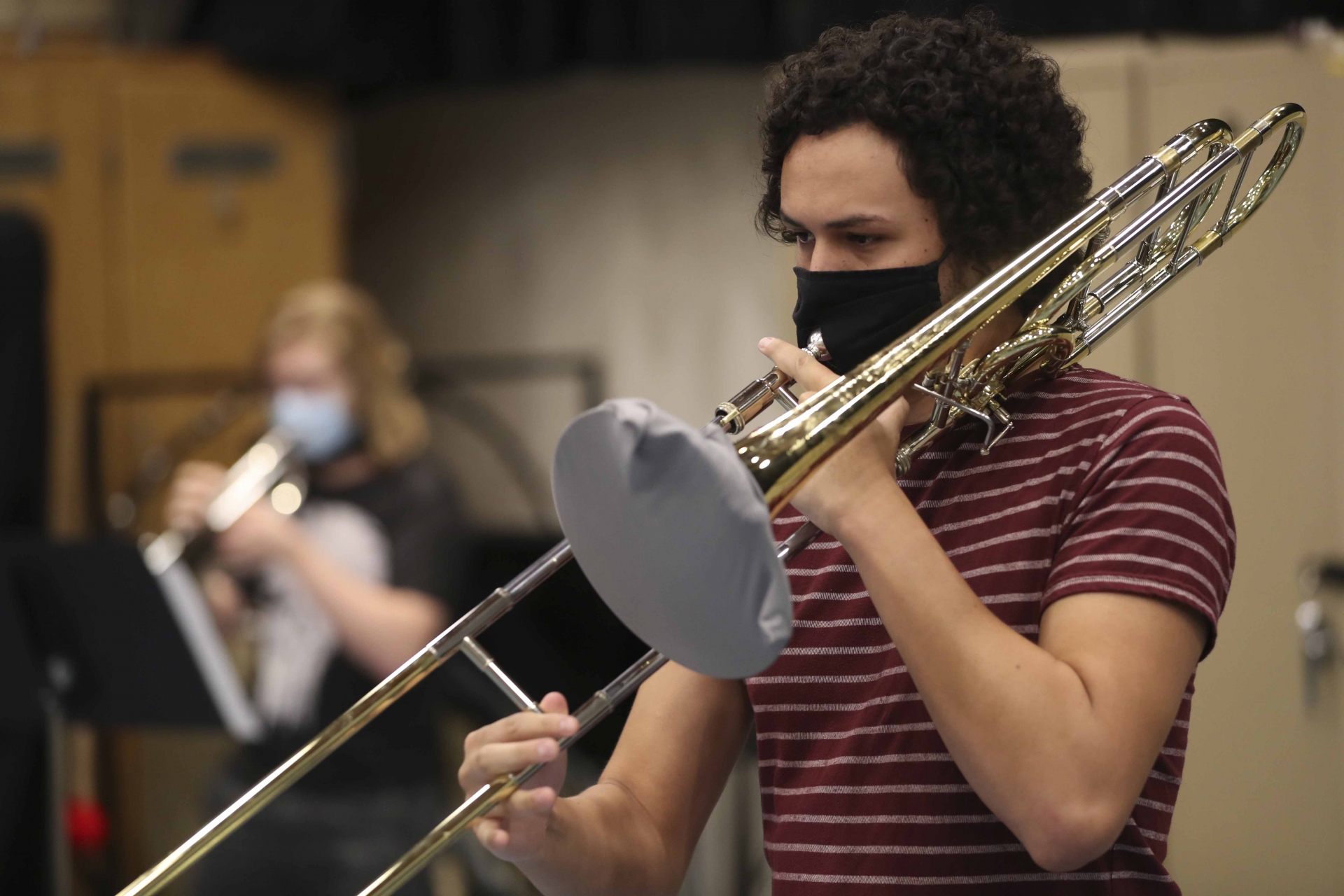 A student plays the trombone while following safety protocol to prevent the spread of COVID-19.
