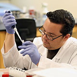 Photo of person using pipet in lab