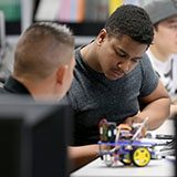 Photo of student at desk constructing robotics