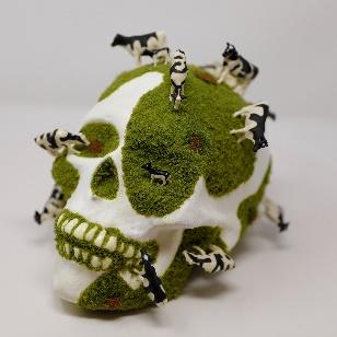 decorated calavera with coarse turf and miniature cow figures