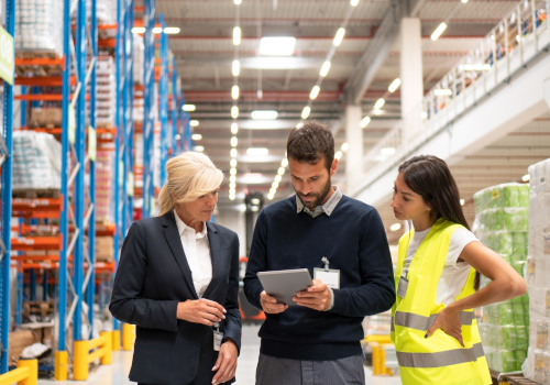 Three people looking over paperwork in a warehouse