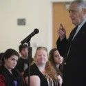 Guy speaking at microphone and audience