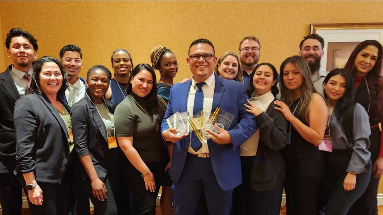 The CSUSB undergraduate and graduate business students who competed at the 2024 International Collegiate Business Strategy Competition pose with their faculty advisor, Jose Navarrete-Cruz, who is holding the trophies the students won.