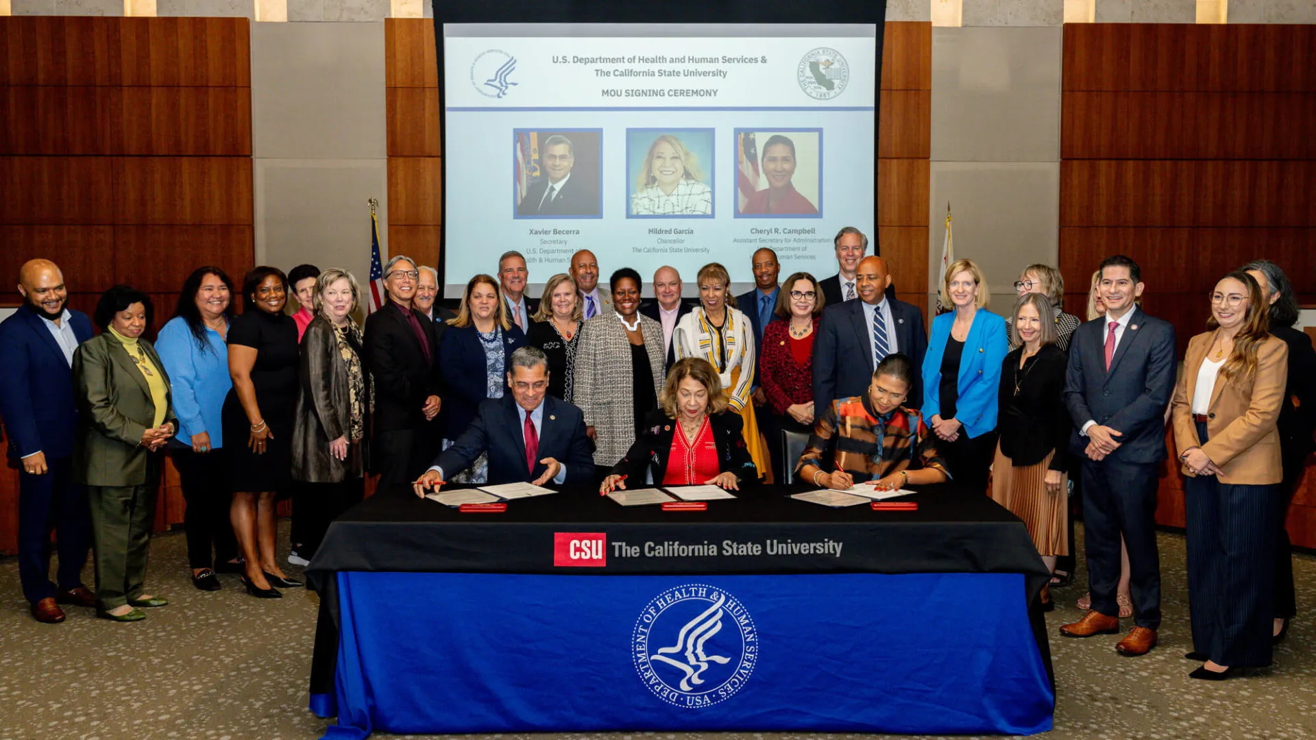 A group of people look on as HHS and CSU officials sign documents.