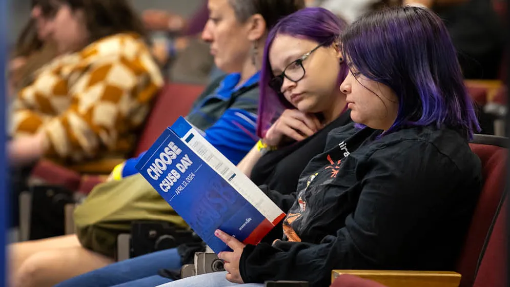 Two people looking over the Choose CSUSB Day program.