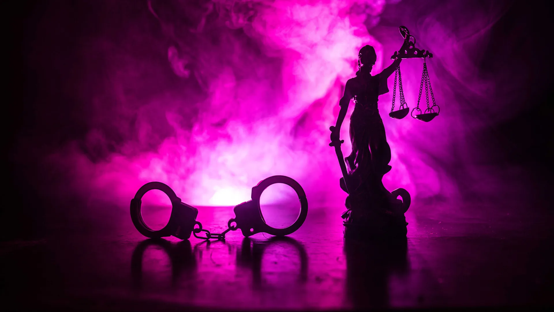 Photo illustration: hand cuffs and statue of Lady Justice against a backdrop of purple fog.