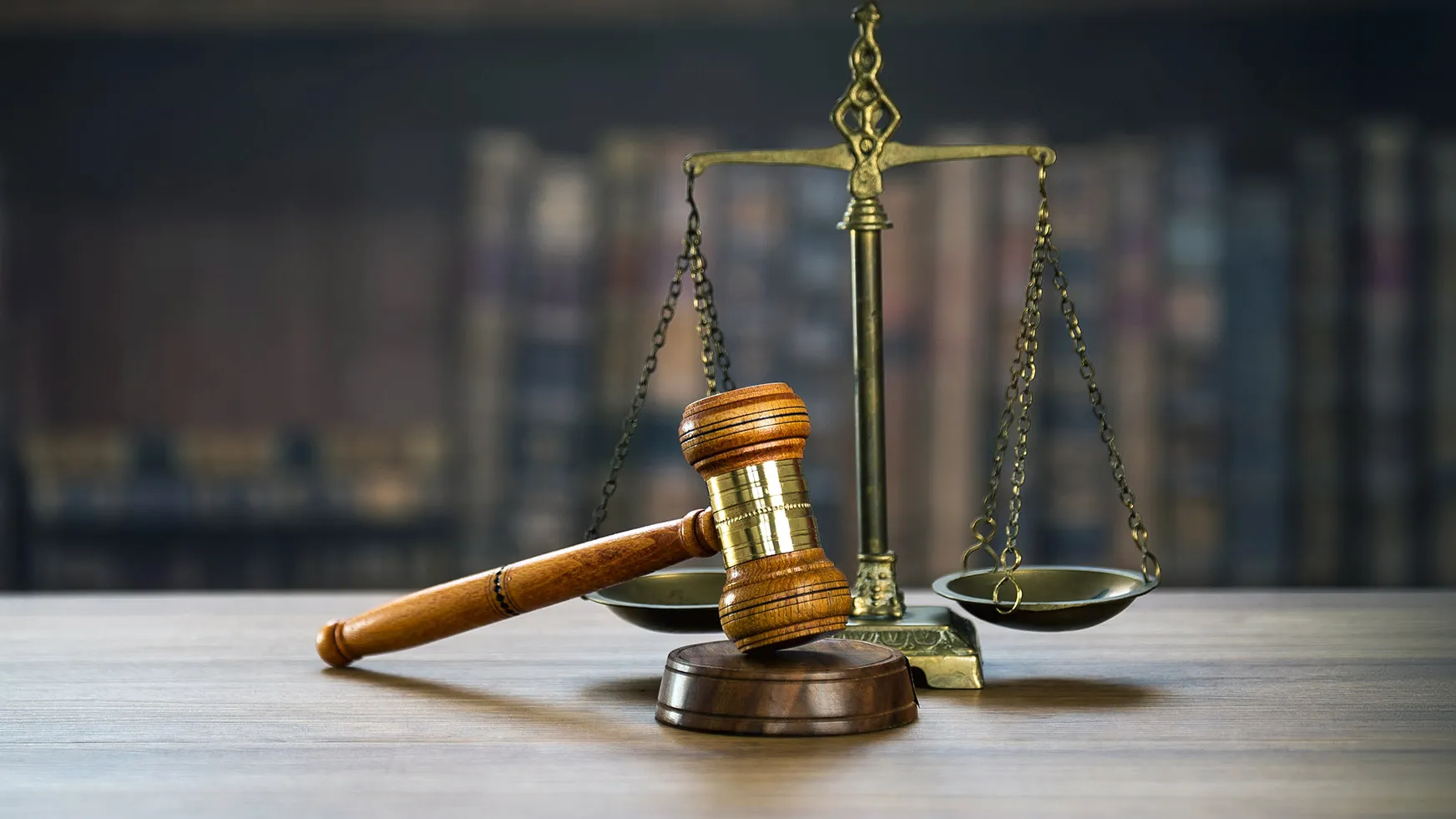 Illustration of a scale and gavel representing justice, against a dark background of books.