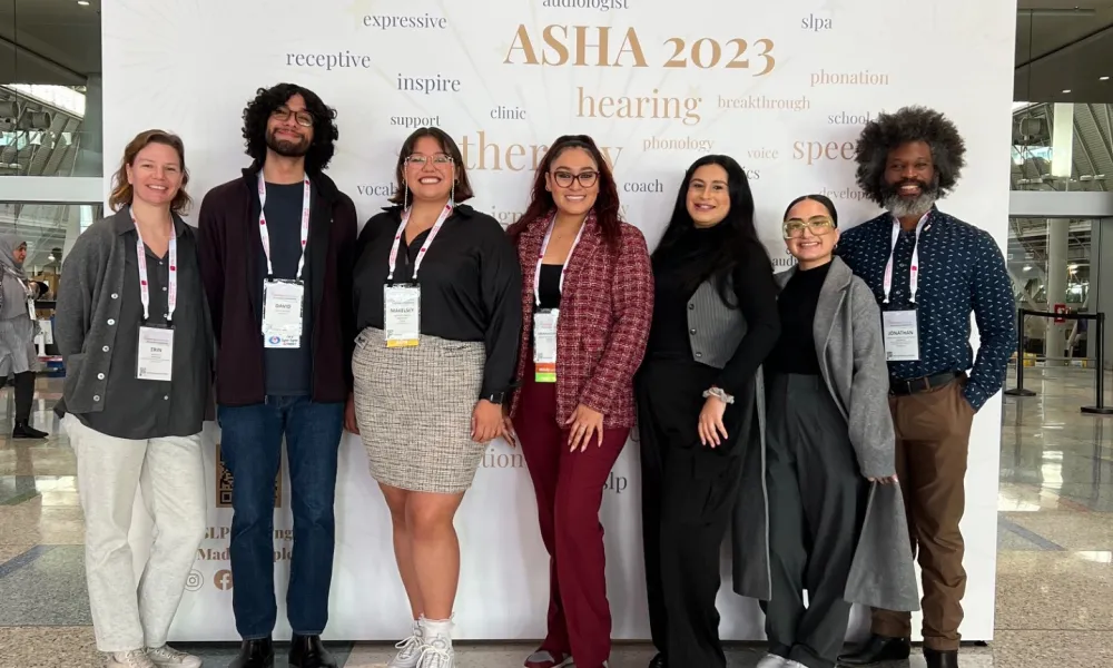 Faculty and students smiling in from of an ASHA sign
