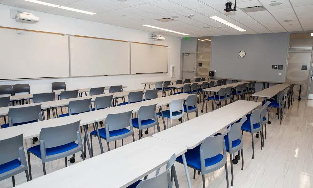 Room set classroom style looking towards large whiteboards.