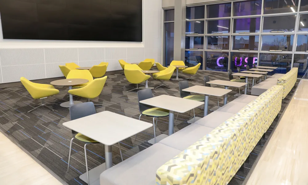 A well-lit, flexible conference room with a digital presentation wall and seating arrangements.