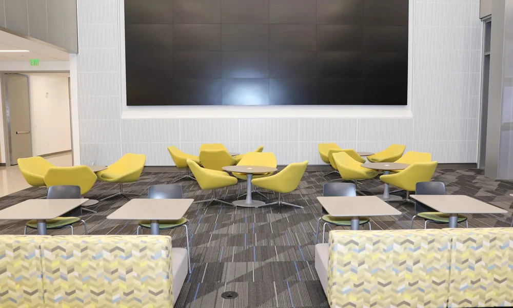 A large, open meeting space with comfortable seating and a high-definition media screen.