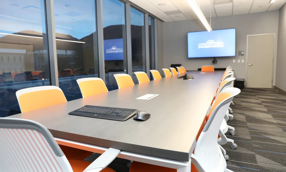  A high-tech conference room equipped with a large digital screen, built-in cameras, and wireless connectivity.