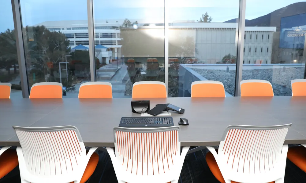 A contemporary boardroom featuring a long table, comfortable chairs, and built-in AV technology.