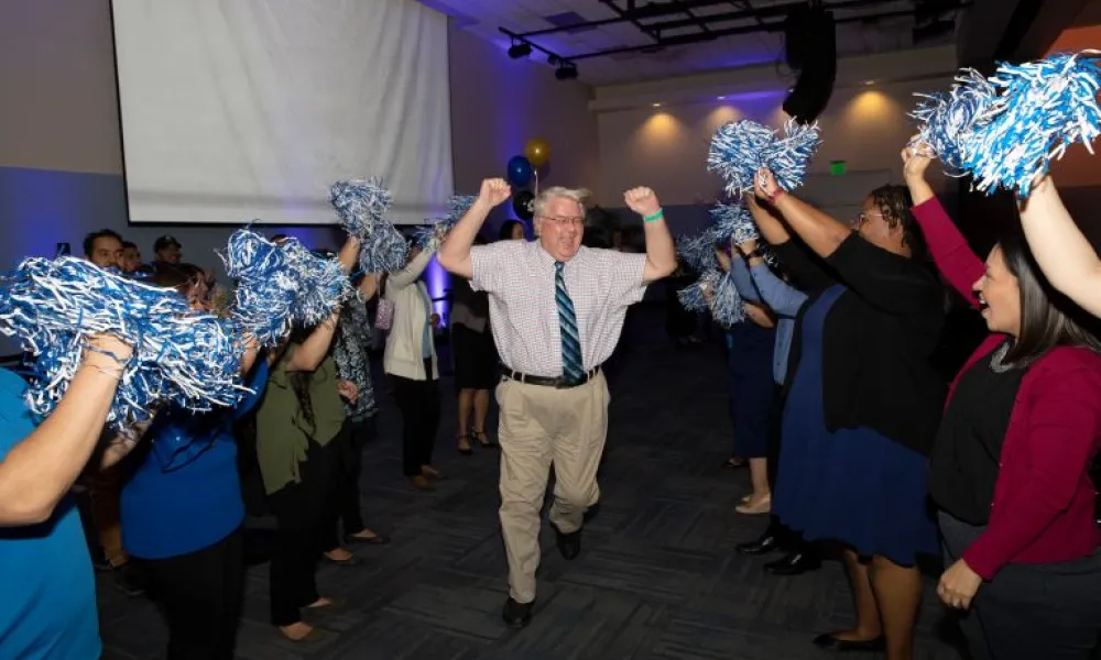 Faculty member running as staff cheers for him. 