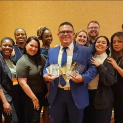 The CSUSB undergraduate and graduate business students who competed at the 2024 International Collegiate Business Strategy Competition pose with their faculty advisor, Jose Navarrete-Cruz, who is holding the trophies the students won.