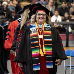 Carmen Beckin commencement regalia, walking at the front of a line of people.