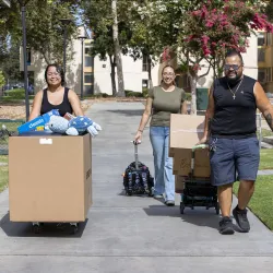 Three people moving items to a CSUSB residential hall on one of three Move-in Days before the start of the 2026 fall semester.