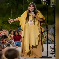 A woman speaking on stage to a crowd of people at CSUSB on California Native American Day
