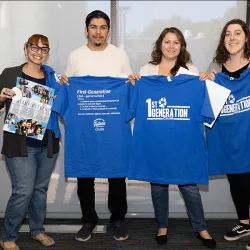 Four attendees hold up first-generation T-shirts they received at the event