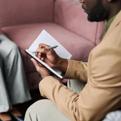 A man taking notes while speaking with a client 