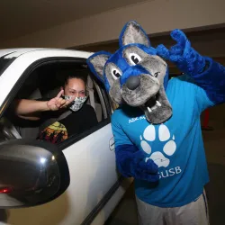 Cody Coyote, CSUSB's mascot, and a student at the Ask Me! drive-thru event on Aug. 24, the first day of the fall semester.