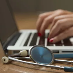 Illustration of a medical professional and a laptop computer.